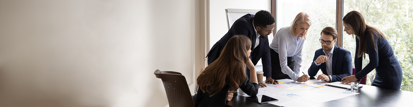 A group of young professionals gathered around a desk in a modern office